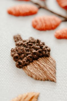 a close up of a knitted object with leaves on the ground next to it