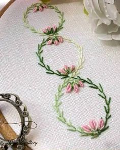 a close up of a embroidery on a hoop with flowers in the middle and a pair of scissors next to it