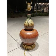 a lamp that is sitting on top of a stand in the middle of a sidewalk