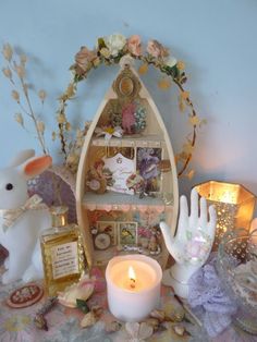 a table topped with candles and figurines next to a shelf filled with items