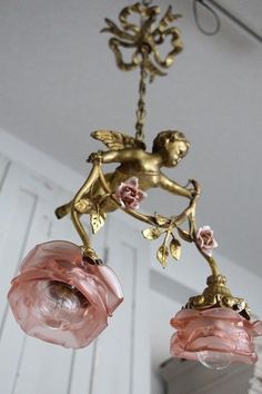 an antique chandelier with pink glass flowers and cherubs hanging from it