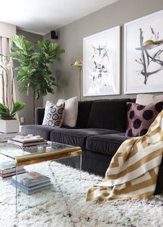 a living room with black couches and white furnishs on the floor, coffee table