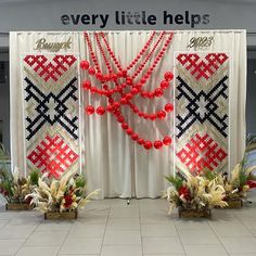 two vases filled with red balls and plants in front of a white backdrop that says every little help