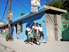 four young people standing in front of a blue building on the side of the road