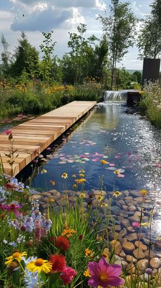 a wooden bridge over a small pond filled with water and colorful flowers on the side