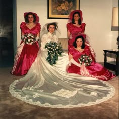 three women in dresses and hats are posing for a photo with one another on the floor