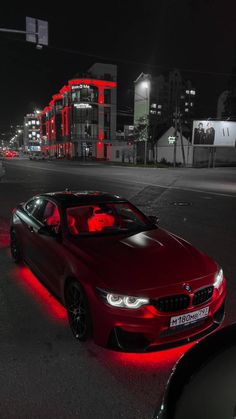 a red car parked in the middle of a street at night with lights on it