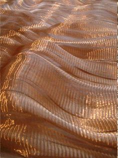 a close up view of a bed with gold colored fabric on it's cover