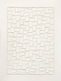 an abstract painting with white squares and lines on the wall, in front of a plant