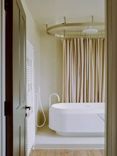 a white bath tub sitting next to a wooden floor