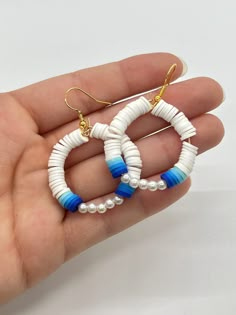 a pair of white and blue hoop earrings on a person's palm holding it in their hand