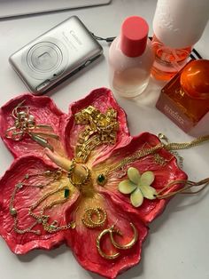 a red flower shaped purse sitting on top of a white table next to other items