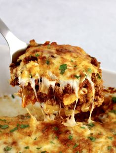 a spoon full of lasagna casserole with meat and cheese on it