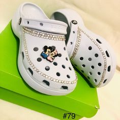 a pair of white crocs with mickey mouse brooch sitting on top of it