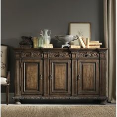 an ornately decorated sideboard with books and vases on top