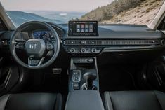 the inside of a car with dashboard, steering wheel and display screen showing various features