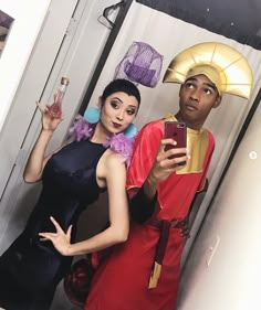 a man and woman in costumes taking a selfie with a cell phone while standing next to each other