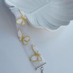 a white bracelet with yellow beads on it next to a silver chain and a bowl