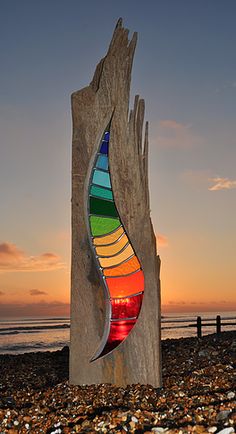 a colorful sculpture on the beach at sunset