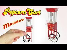 a hand is pointing at an old fashioned popcorn cart