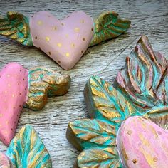 three heart shaped cookies sitting on top of a table next to other hearts and leaves