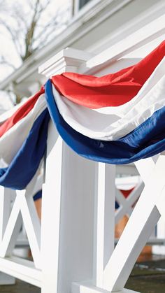 two white chairs with red, white and blue ribbons on them