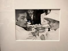 a black and white photo of two people sitting at a table with food in front of them