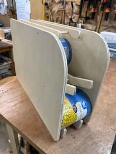 a wooden table topped with an open storage bin filled with cans and corn kernels