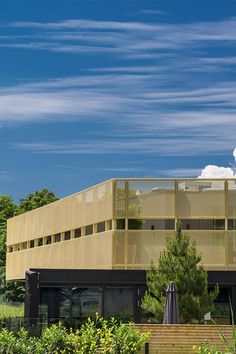 a large building sitting next to a lush green forest filled with lots of trees and bushes