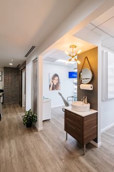 a bathroom with wood flooring and a sink in the center, along with a large mirror on the wall