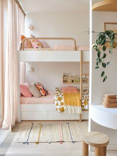 two bunk beds in a room with plants on the wall and rugs on the floor