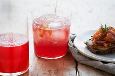 two glasses and a plate with food on it next to a pitcher filled with liquid