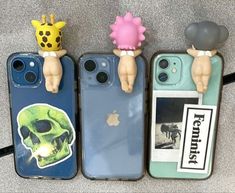 three cell phones are lined up in a row with fake heads attached to the back