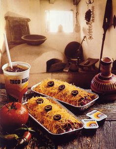 two pans filled with food sitting on top of a table next to tomatoes and peppers