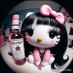 a hello kitty figurine next to a bottle of whiney wine on a table