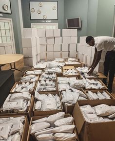 a man standing in front of boxes filled with white bags and packages on the floor