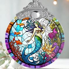 a stained glass pendant with an image of a mermaid on it