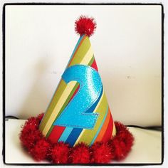 a birthday hat with the number two on it and pom - poms around it