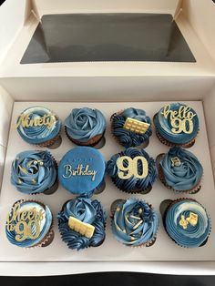 cupcakes with blue frosting and gold decorations in a box