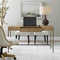 a laptop computer sitting on top of a wooden desk next to a lamp and chair