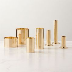 several different sized gold candles on a white table