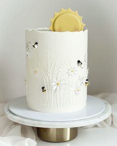 a white and gold decorated cake on a platter with a yellow object in the middle