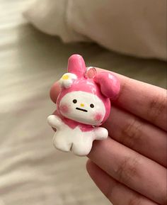 a hello kitty keychain is held in someone's hand while wearing a pink bow