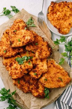 chicken cutlets with parsley on parchment paper next to bowl of sauce and fork