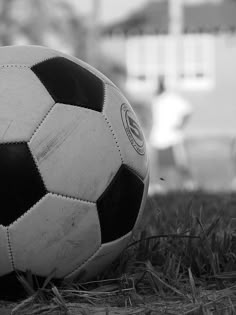 a black and white photo of a soccer ball on the grass in front of a building