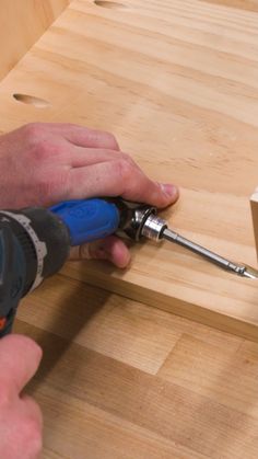 a person using a drill to attach the screws on a piece of plywood