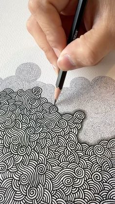 a person is drawing on paper with a pencil and pen, while the image appears to be black and white