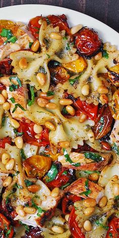 a white plate topped with pasta and veggies on top of a wooden table