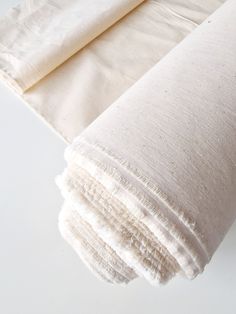 two pieces of cloth folded on top of each other, one white and the other beige