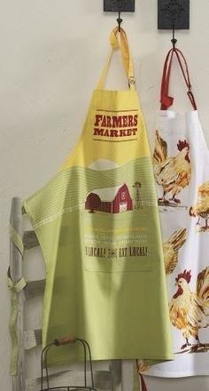 two aprons hanging from hooks on a wall